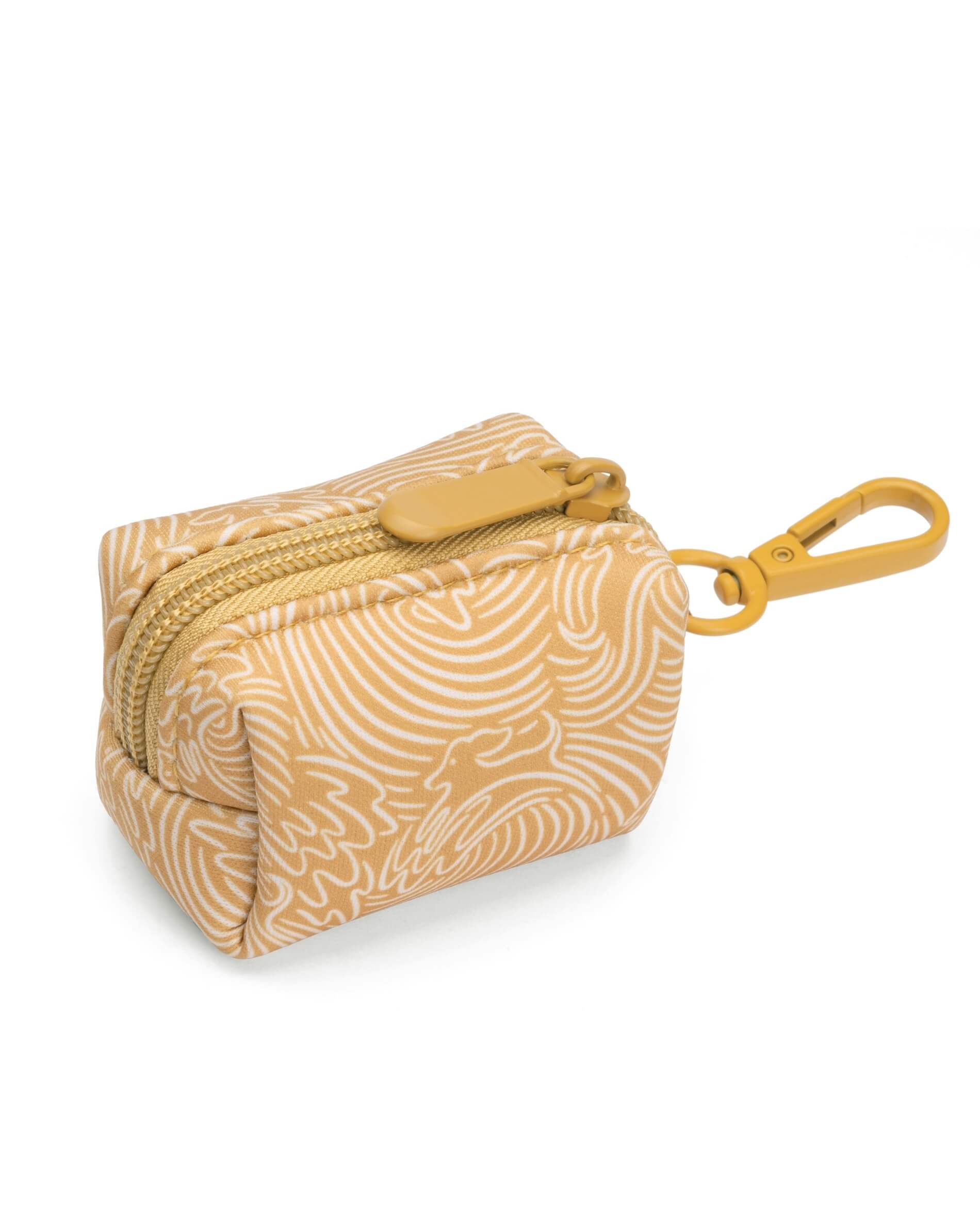 A small gold-colored dog poop bag holder with a clip for leash attachment and a white ocean-wave pattern.